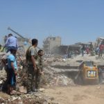 People look for survivors under debris at a damaged site after two bomb blasts claimed by Islamic State hit the northeastern Syrian city of Qamishli